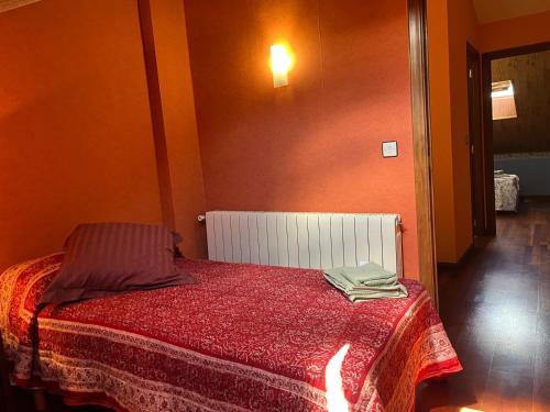 a small bedroom with a bed with a red blanket at Alojamiento Las Endrinas in Ezcaray