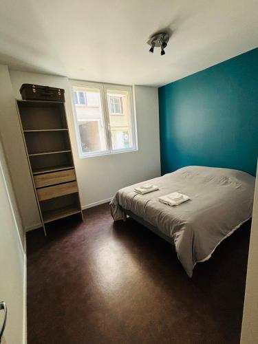 une chambre avec un lit et un mur bleu dans l'établissement Appartement plein centre du puy en velay avec parking, au Puy-en-Velay