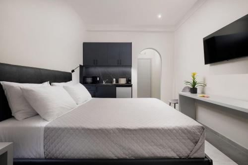 a bedroom with a white bed and a kitchen at Ilios Properties - next to Gouvia Beach in Gouvia