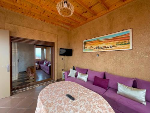 a living room with a purple couch and a tv at Petite villa palmeraie d Aglou in Tiznit