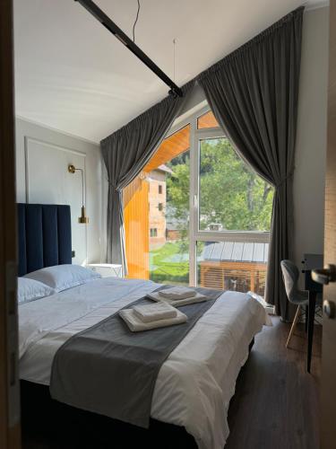 a bedroom with a large bed and a large window at The NEST Villa in Borşa