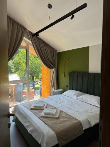 a bedroom with a large bed and a large window at The NEST Villa in Borşa