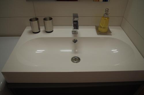 Un lavabo blanco con dos botellas y un dispensador de jabón. en Duplex avec terrasse vue mer et parking, en La Ciotat