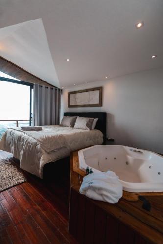 a bedroom with a bed and a bath tub at Pousada Dona Pedra - Cabana Opala in Córrego do Bom Jesus