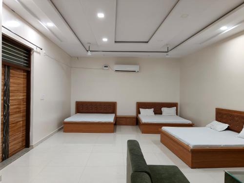 ein Zimmer mit 2 Betten und einem Sofa darin in der Unterkunft GURU KRIPA GARDEN in Govardhan