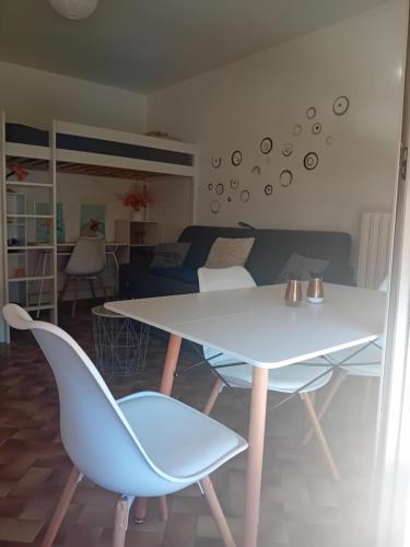 une salle à manger avec une table et des chaises blanches dans l'établissement Les pinèdes, à Sète
