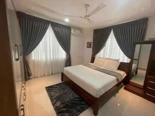 a bedroom with a bed and two large windows at Stylish 1 Bedroom Apartment in Ogbojo