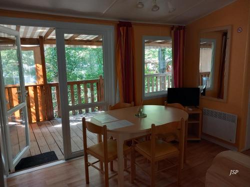 a dining room with a table and a balcony at Mobil-home Riviera in Vaudreuille
