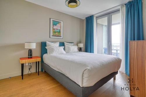 une chambre avec un grand lit avec des rideaux bleus dans l'établissement Le Vivant - À Auteuil - 359B, à Paris