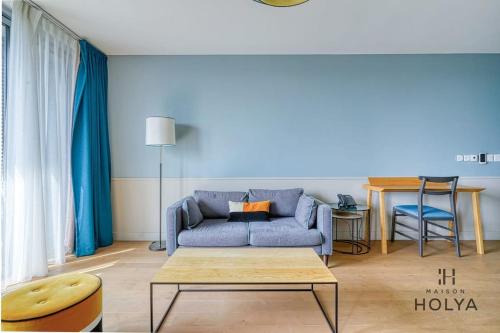 un salon avec un canapé bleu et une table dans l'établissement Le Vivant - À Auteuil - 359B, à Paris