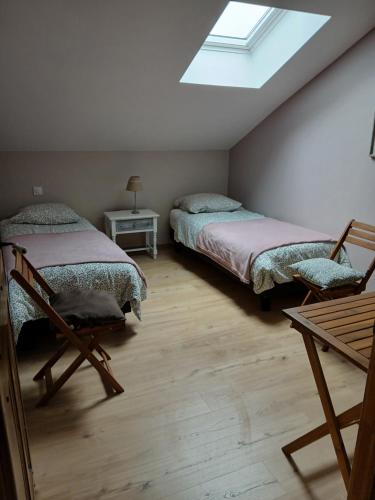 a attic bedroom with two beds and a skylight at la clé du bouton d'or in Leschelles