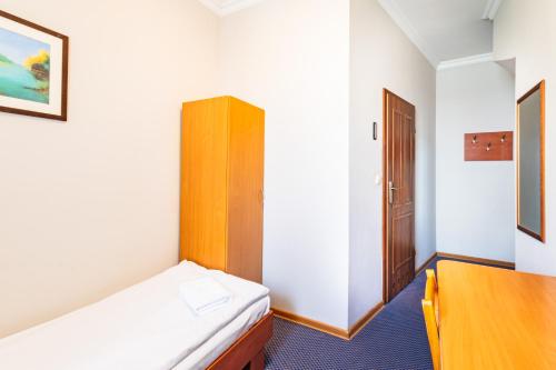 a small room with a bed and a wooden cabinet at Noclegi Stadion Bed & Breakfast in Warsaw
