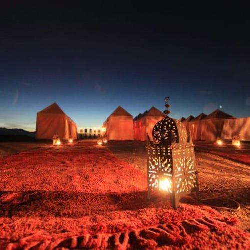 a group of tents with lights in the desert at night at Agafay country club in Tafza