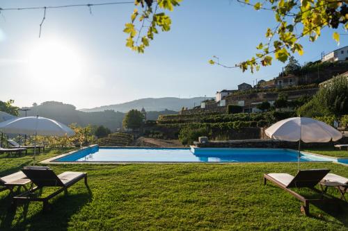 una piscina con due sedie e ombrelloni sull'erba di Casa d' Alem a Mesão Frio