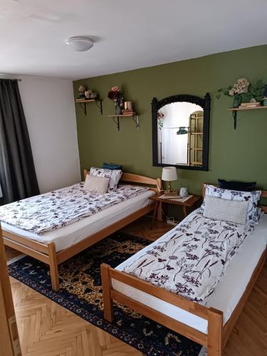 deux lits dans une chambre aux murs verts dans l'établissement Apartman Ohren, à Sarajevo