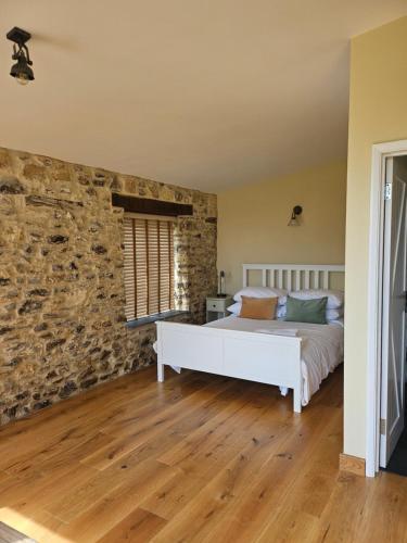 a bedroom with a bed and a stone wall at The Drewe Arms, Broadhembury in Broadhembury