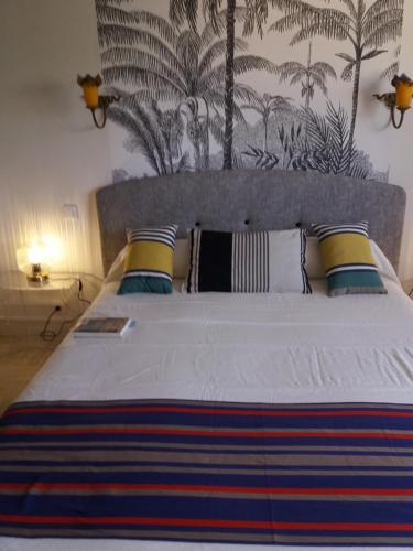 - une chambre avec un grand lit blanc et du papier peint tropical dans l'établissement biarritz cote des basques VUE SUR MER, à Biarritz