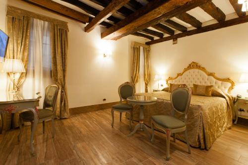 a bedroom with a bed with chairs and a table at Hotel Al Ponte Mocenigo in Venice