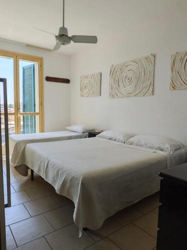 two beds in a white room with a window at Appartamento con posto auto in Viareggio