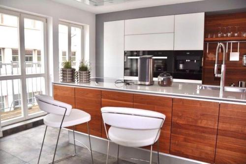 a kitchen with white and wood cabinets and white stools at SH-Apartment Penthouse 44 - zentral & einzigartig in Erfurt