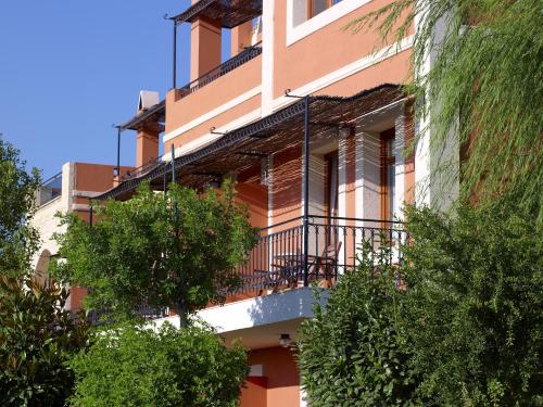 a building with a balcony and trees in front of it at Katalagari Country Suites in Archanes
