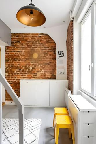 Cette chambre dispose d'un bureau blanc et d'un mur en briques. dans l'établissement Casa Naranja, à Paris