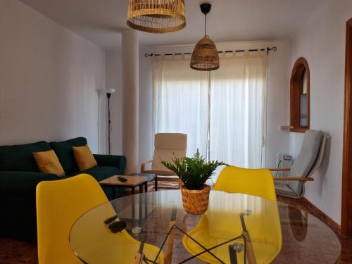 ein Wohnzimmer mit gelben Stühlen und einem Glastisch in der Unterkunft Torete in Roquetas de Mar
