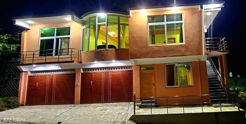 a large house with a red garage at night at Mashal Palace Apartment's in Nathia Gali