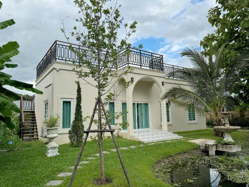 a large white house with a tree in the yard at Villa Lacroix Organic Farm in San Pa Tong