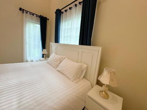 a bedroom with a white bed and a window at Villa Lacroix Organic Farm in San Pa Tong