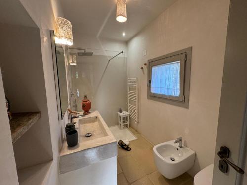 a white bathroom with a sink and a toilet at Dimora Dei Semplici in Ostuni