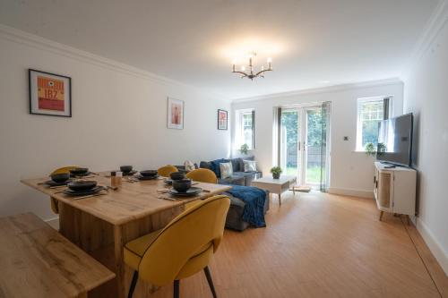 a living room with a wooden table and yellow chairs at Emirates House, Luxe 5 Bed, with King sized Beds, next to Aiport & NEC, JLR 5 mins in Marston Green