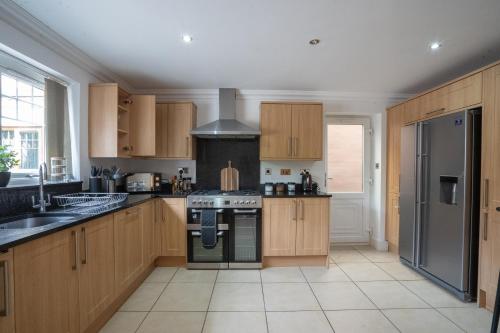 a kitchen with wooden cabinets and a stove at Emirates House, Luxe 5 Bed, with King sized Beds, next to Aiport & NEC, JLR 5 mins in Marston Green