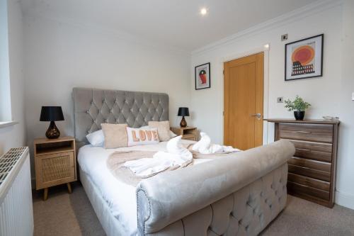 a bedroom with a large bed with white sheets at Emirates House, Luxe 5 Bed, with King sized Beds, next to Aiport & NEC, JLR 5 mins in Marston Green