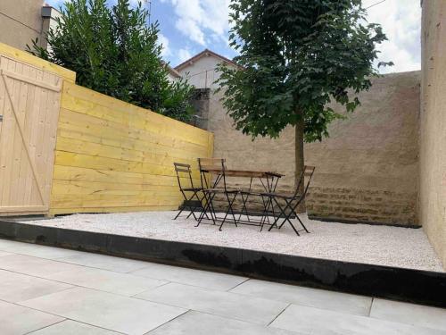 a table and chairs next to a fence with a tree at Les Minoteries Aux portes de la gastronomie in Dijon
