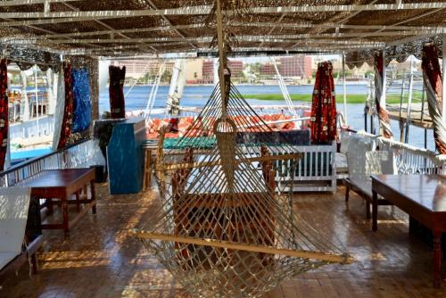 a hammock on a boat with tables and benches at Cinderella Malika in Al Bayāḑīyah
