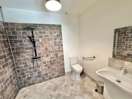 a bathroom with a brick wall next to a toilet at Plain-pied avec terrasse à 5 minutes de Berck in Verton