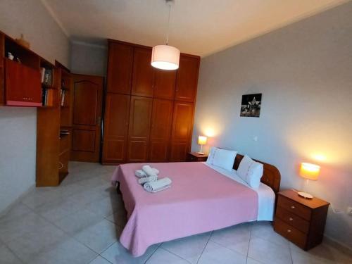 a bedroom with a pink bed with two towels on it at MetaxiasAndMariasHouse in Leonidion