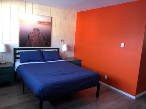 a bedroom with a blue bed and an orange wall at Canterbury Inn in Invermere