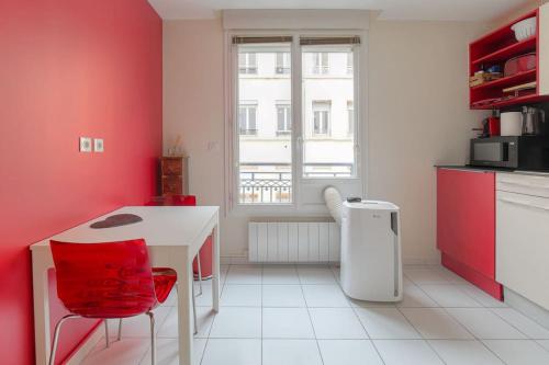 - une cuisine avec des murs rouges, une table blanche et des chaises dans l'établissement Appartement fonctionnel et bien situé, coeur 6ème, à Lyon