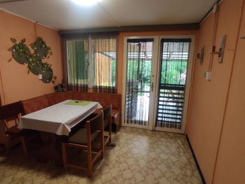 comedor con mesa, sillas y puertas correderas de cristal en Borgáta Retro Apartman, en Borgáta