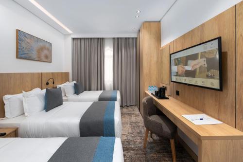 a hotel room with two beds and a desk at فندق السعفة الذهبية Assaafa Golden Hotel in Al Madinah