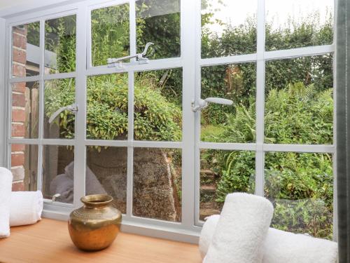 a room with a large window looking out at a garden at Hole Farm Stables in Newton Abbot