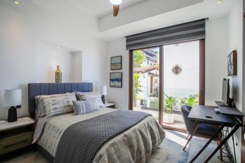 Un dormitorio con una cama y un escritorio y una ventana. en Ocean View 2BD Retreat with Pool, en Puerto Vallarta