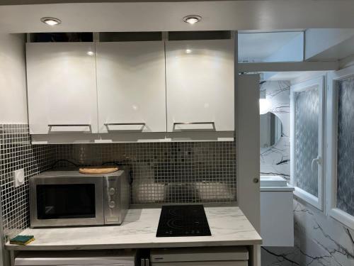 une cuisine avec des armoires blanches et un micro-ondes dans l'établissement Studio à 2 minutes de lafayette, à Paris
