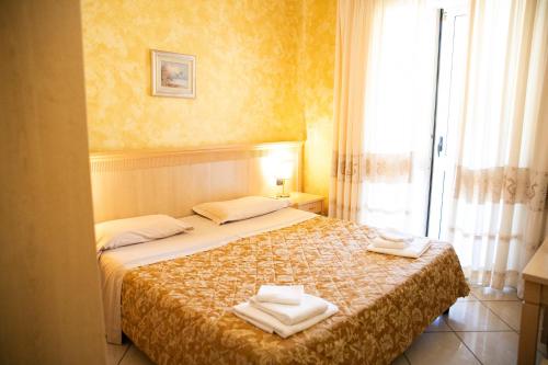 a bedroom with a bed with two towels on it at Mannu Hotel in Bosa