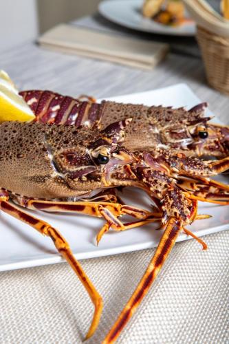 a large lobster on a white plate on a table at Mannu Hotel in Bosa