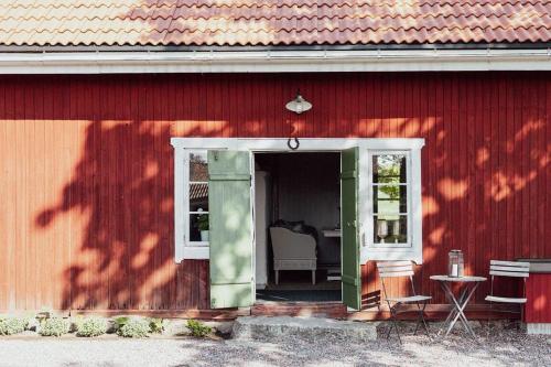 a red building with a door and a chair in it at Bagarstugan på Grindtorp in Enköping