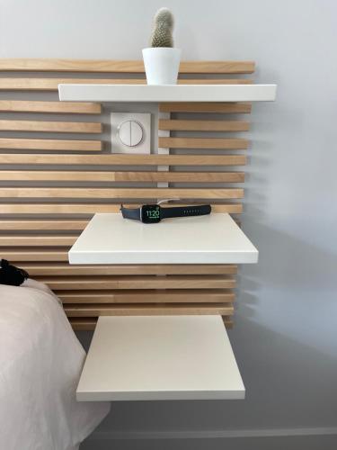 a bed with a watch and a cactus on a wall at Appart du faubourg in Valence