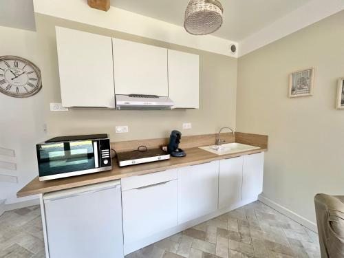 a kitchen with white cabinets and a microwave at Maison - 2 chambres - Terrasse - Babyfoot in Verton